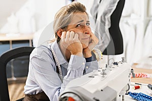 Stressed seamstress sewing in the workshop studio for sewing machine. Workplace of seamstress