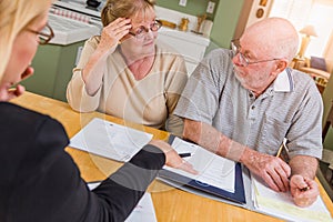 Stressed Senior Adult Couple Going Over Documents in Their Home with Agent At Signing