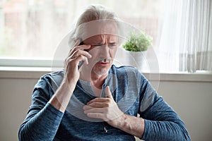 Stressed senior man having heart attack while talking on phone
