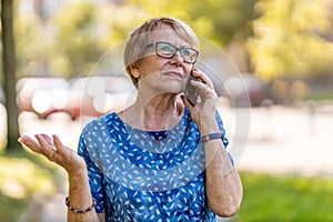 Stressed senior woman using mobile phone outdoors