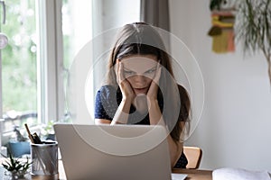 Stressed shocked young woman frustrated about problems with laptop