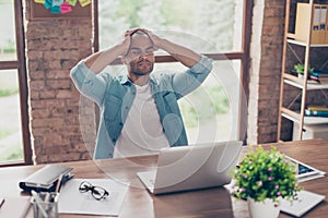 Stressed sick mulatto freelancer is having headache and thinking how to finish his work. He is in a casual smart, at his home offi