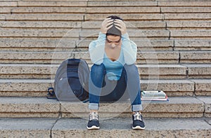 Stressed student girl sitting on the steps outdoors