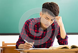 Stressed student studying for exam in classroom