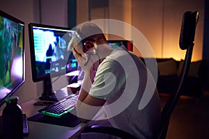 Stressed Teenage Boy Being Bullied Online Whilst Gaming At Home