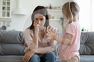 Stressed thoughtful 30s mother ignoring playful happy small daughter.