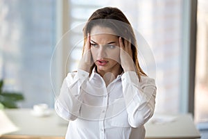 Stressed tired businesswoman in panic feeling headache at work