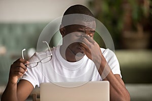 Stressed tired from computer work african man feeling eye strain photo