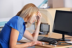 Stressed UK doctor sitting at desk photo