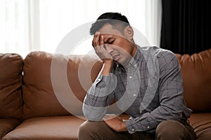 Stressed and upset Asian man is covering his face, crying about his failures in life