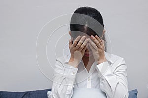 Stressed upset young Asian woman with hands on face  sitting in living room