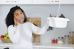 Stressed woman calling plumber to fix water leaking from ceiling