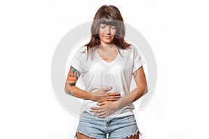 A stressed woman clutched her stomach in pain. White background. Copy space. Concept of diseases of the stomach