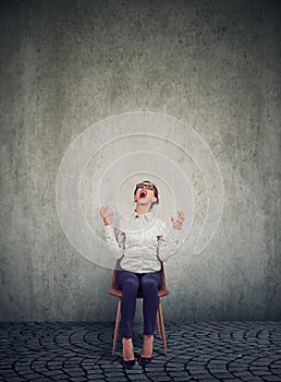 Stressed woman company employee sitting on a chair screaming in desperation