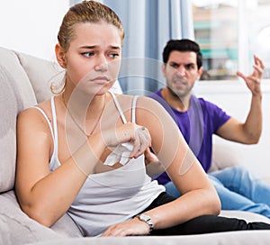 Stressed woman on couch with disgruntled husband