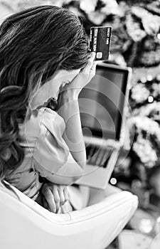 Stressed woman with credit card and laptop in front of chr