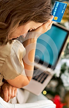 Stressed woman with credit card and laptop in front of chr