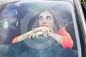 Angry female driver driving a car. Angry young woman stuck in a traffic jam. Woman annoyed in car. Girl stuck in traffic.