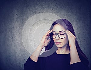 Stressed woman with glasses suffering from eyestrain having headache