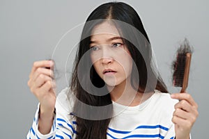 stressed woman having hair loss problem with hairbrush