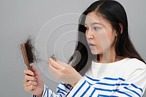 stressed woman having hair loss problem with hairbrush