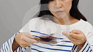 stressed woman having hair loss problem with hairbrush