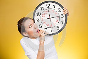 Stressed woman holding clock looking anxiously running out of time