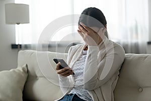 Stressed woman holding smartphone feels humiliated, cyberbullying concept