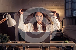 stressed woman at laptop with windblown hair signaling work tension