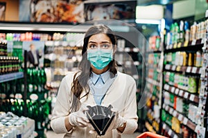 Stressed woman with mask shopping in grocery store with an empty wallet.Bankruptcy/recession.Covid-19 quarantine lockdown impact.