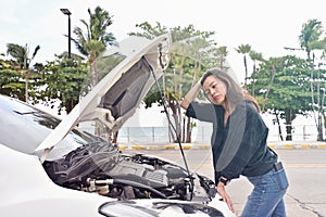 Stressed woman opening hood of broken car