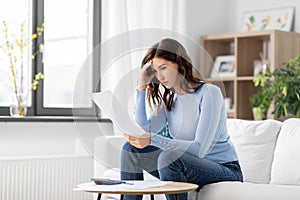 stressed woman with papers and calculator at home