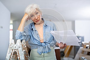 Stressed woman with papers in renovating house