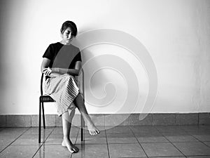 Stressed woman sitting on chair at the left side of wall,with upset and unhappy feeling,depressive disorder syndrome,serious emoti