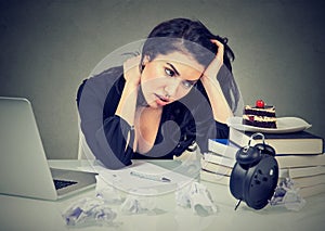 Stressed woman sitting at desk in her office overworked craving sweet cake