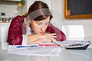 Stressed woman sitting at home and checking unpaid bills