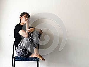 Stressed woman sitting with a knee high on chair,at the left side of background,raise hand cover mouth,open eye widely,with upset