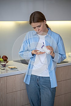 Stressed woman suffering depression taking antidepressants neuroleptics on kitchen at home.