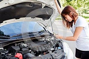 Stressed woman taking photo of engine with mobile phone - car br