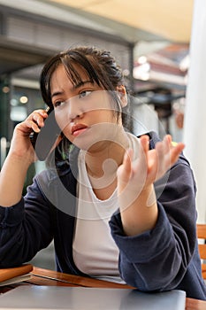 A stressed woman is talking on the phone, having a serious conversation with someone