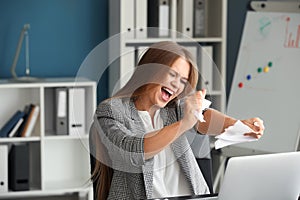 Stressed woman tearing paper in office