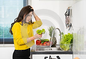 Stressed woman washing vegetables in the sink in the kitchen at home