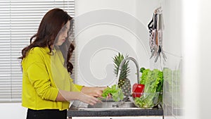 Stressed woman washing vegetables in the sink in the kitchen at home