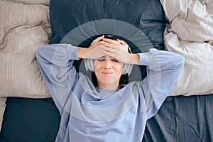 Stressed Woman Wearing Headphones Lying in Bed