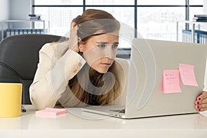 Stressed woman working with laptop computer on desk in overworked