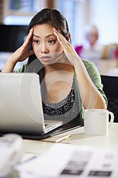 Stressed Woman Working At Laptop In Contemporary Office