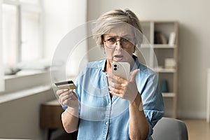 Stressed worried elderly pensioner woman having problems with credit card