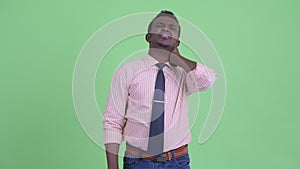 Stressed young African businessman having neck pain