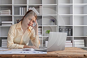 Stressed young Asian businesswoman focuses on rechecking the business financial investment plan& x27;s report at her desk