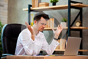 Stressed young businessman shocked by bad news using laptop at work, desperate bankrupt investor lost money, financial problem